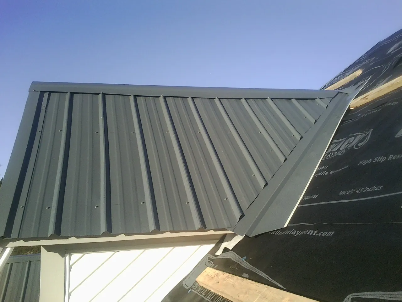 Gray metal roof panels going on over a garage gable in Cove City
