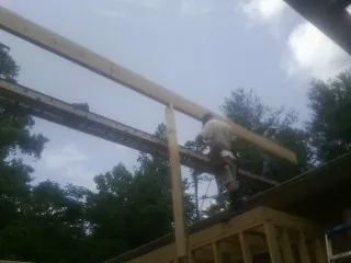 Carpenter setting a ridge beam over a new addition frame — Ice Dam Removal by Roofing Brothers in Cove City