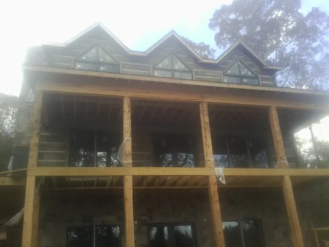 Dormers and porch framing on a large log home under construction — Roof Coating work by our crew in Cove City