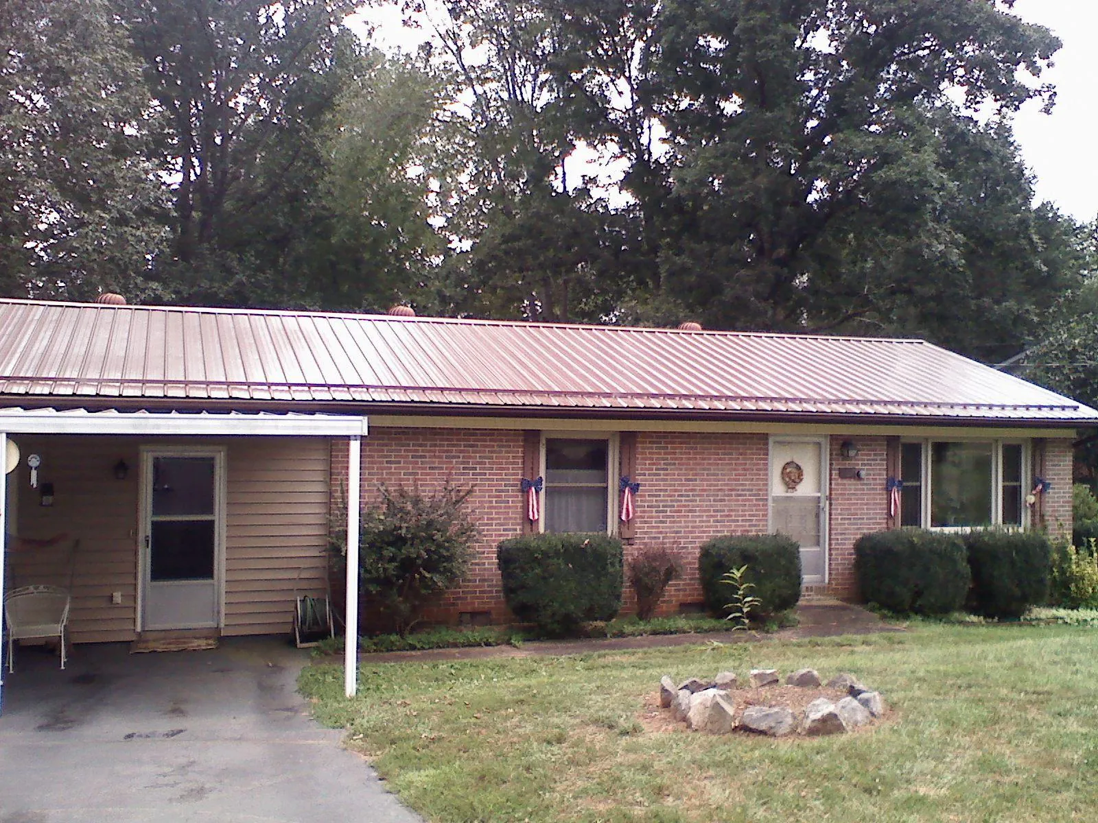 Bronze metal roof and carport on a brick ranch home — Roof Repair work by our crew in Cove City