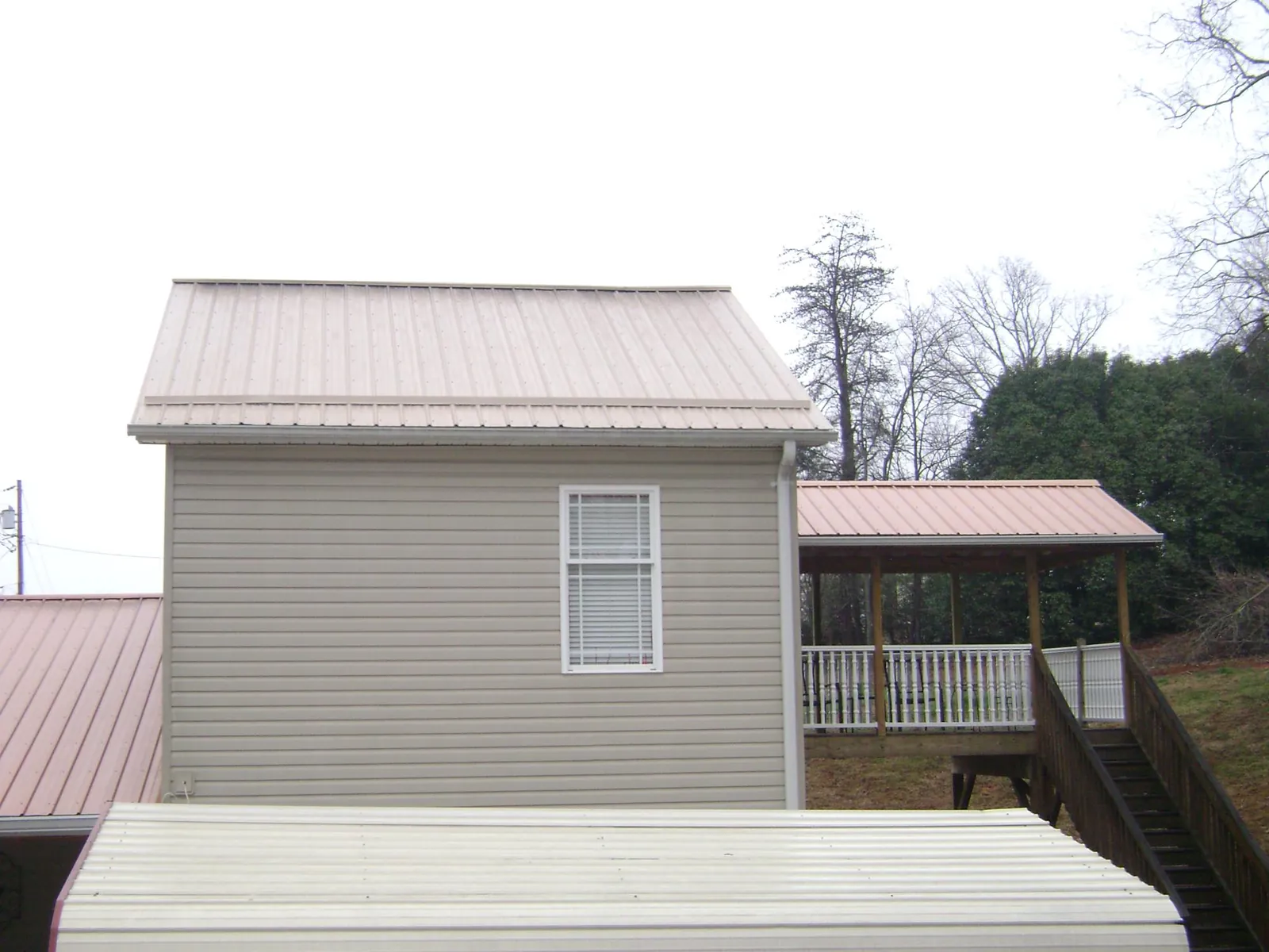 Tan metal roofs on a two story addition and attached porch, from a Roof Replacement job in Cove City